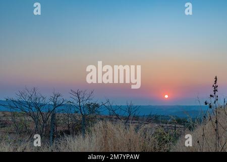 Un coucher de soleil sur une montagne. Les rayons du soleil qui brillent sur les sommets créent une gamme de couleurs, allant des oranges chaudes et jaunes aux violets et bleus frais. Banque D'Images