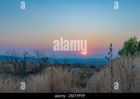 Un coucher de soleil sur une montagne. Les rayons du soleil qui brillent sur les sommets créent une gamme de couleurs, allant des oranges chaudes et jaunes aux violets et bleus frais. Banque D'Images