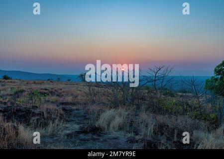 Un coucher de soleil sur une montagne. Les rayons du soleil qui brillent sur les sommets créent une gamme de couleurs, allant des oranges chaudes et jaunes aux violets et bleus frais. Banque D'Images