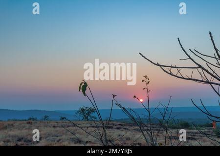 Un coucher de soleil sur une montagne. Les rayons du soleil qui brillent sur les sommets créent une gamme de couleurs, allant des oranges chaudes et jaunes aux violets et bleus frais. Banque D'Images