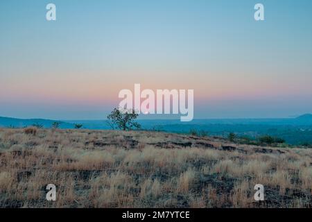 Un coucher de soleil sur une montagne. Les rayons du soleil qui brillent sur les sommets créent une gamme de couleurs, allant des oranges chaudes et jaunes aux violets et bleus frais. Banque D'Images