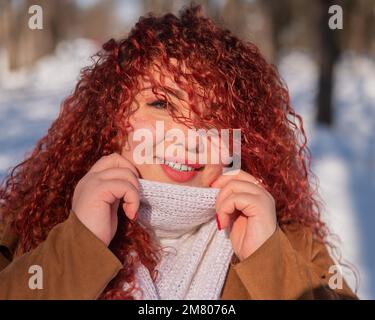 Portrait d'une femme souriante aux cheveux rouges lors d'une promenade en hiver. Banque D'Images