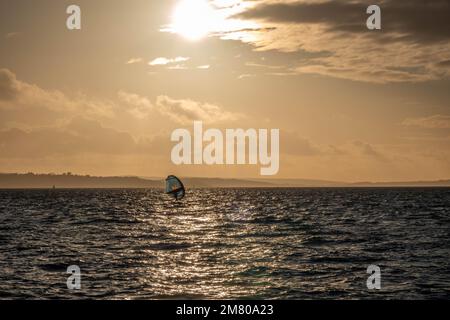 Planche à voile à Hill Head Hampshire Angleterre avec l'île de Wight et une brume orange du soleil se coucher en arrière-plan Banque D'Images