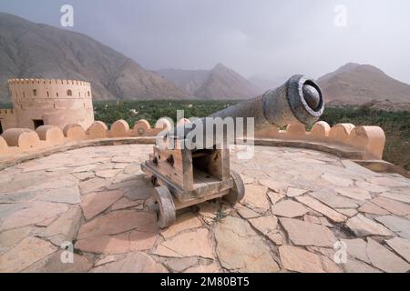 Nakhal, Oman - 04.01.2018: Canon dans la cour intérieure du fort arabe médiéval de Nakhal, Oman. Murs fortifiés, roche, sol en pierre, ciel bleu Banque D'Images