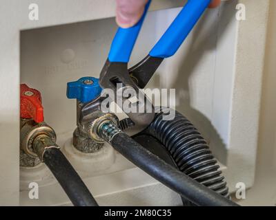 Plomber à l'aide d'une clé pour fixer la conduite d'alimentation en eau à la vanne d'arrêt du lave-linge. Banque D'Images