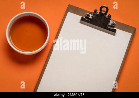 presse-papiers avec un papier vierge, plan de travail avec une tasse de thé Banque D'Images