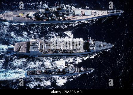 Une vue aérienne à tribord du centre de l'huileur USS KANSAS CITY (AOR-3), fournissant une reconstitution en cours au cuirassé USS NEW JERSEY (BB-62), en haut, et au destroyer de missile guidé USS BUCHANAN (DDG-14). Pays : Océan Pacifique (POC) Banque D'Images