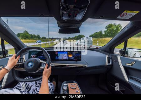 Belle vue intérieure de la voiture électrique BMW iX40 avec femme conducteur. Banque D'Images