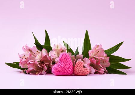 Composition de fleurs violettes Alstroemeria avec un coeur tricoté rose sur fond rose. Concept de la Saint-Valentin, salutations pour un être cher, top vi Banque D'Images