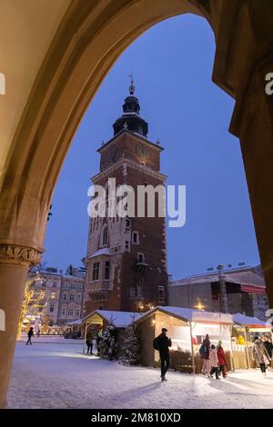 Scène sous une arche de la salle de la toile médiévale du marché de Noël de Cracovie et de la tour de l'Hôtel de ville la nuit, vieille ville de Cracovie, Cracovie Pologne Banque D'Images