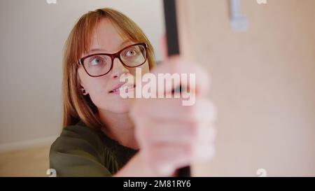Gros plan sur une jeune femme du caucase qui ouvre un placard. Photo de haute qualité Banque D'Images