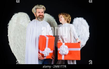 Anges de Saint-Valentin avec boîte cadeau. Père et fils heureux en costume d'ange avec cadeaux. Banque D'Images