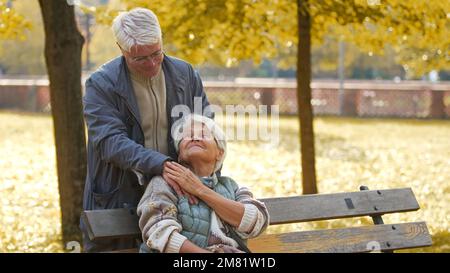Un vieil homme souriant reposant sa main sur son épaule de femme à l'extérieur. Photo de haute qualité Banque D'Images