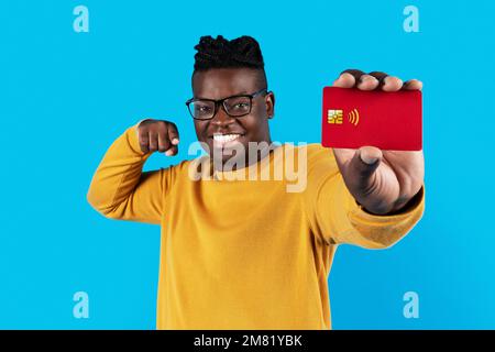 Heureux Africain américain homme pointant vers la carte de crédit rouge dans sa main Banque D'Images