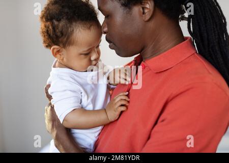 Concept de garde d'enfants. Père noir aimant tenant son bébé fils mignon dans les bras Banque D'Images