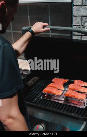 gros plan sur un homme qui met des steaks de saumon frais sur un grill Banque D'Images