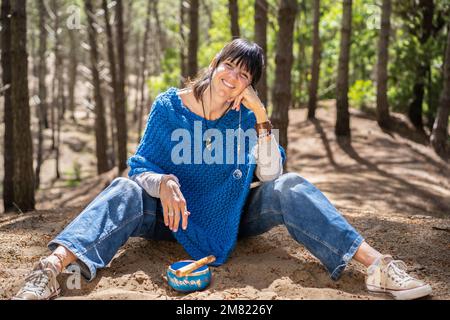 Une femme souriante assise sur le sol tout en regardant l'appareil photo. Banque D'Images
