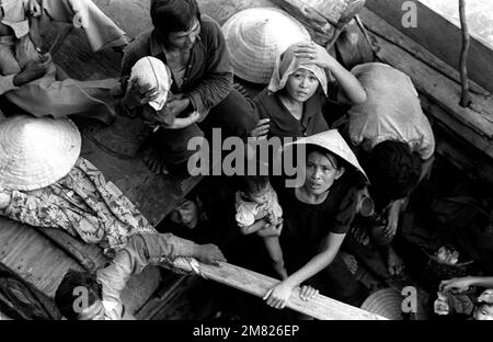 Les réfugiés vietnamiens attendent d'être pris à bord du navire de commandement amphibie USS BLUE RIDGE (LCC 19). Les 35 refuges ont été sauvés d'un bateau de pêche de 35 pieds à 350 milles au nord-est de Cam Ranh Bay, au Vietnam, après avoir passé huit jours en mer. Pays: Mer de Chine méridionale Banque D'Images