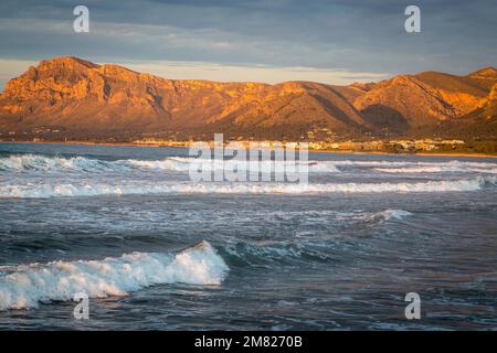 Colonia de Sant Pere dans la lumière du soir, vagues devant, Serres de Llevant montagnes à l'arrière, son Serra de Marina, Majorque, Espagne Banque D'Images