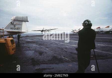 Un avion Trader C-1A arrive pour un atterrissage à bord du porte-avions USS MIDWAY (CV 41). Un avion EA-6B Prowler (à gauche), un Avion A-6 Intruder et un F-4 Phantom II (à droite) sont stationnés sur le pont de vol. Base : USS Midway (CV 41) pays : Océan Pacifique (POC) Banque D'Images