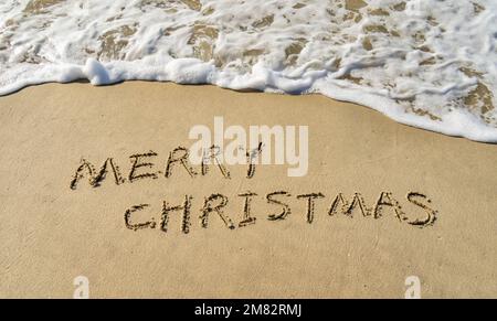 Joyeux Noël manuscrit dans le sable sur une belle plage Banque D'Images