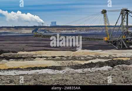 PRODUCTION - 11 janvier 2023, Brandebourg, Welzow: Des tas de déblais et un épandeur peuvent être vus dans la mine de lignite opencast de Welzow-Süd exploitée par Lauritz Energie Bergbau AG (LEAG). En arrière-plan se trouve la centrale au lignite de Schwarze Pumpe. C'est là que la veine de charbon Lusatien de 2nd a été extraite depuis 1959. Pour ce faire, les pelles hydrauliques géantes doivent creuser environ 100 mètres de profondeur dans la terre. La veine de lignite réelle n'a qu'environ 14 mètres d'épaisseur en moyenne. Environ 750 personnes sont employées dans et autour de la mine à ciel ouvert pour extraire le charbon. Le lignite est brûlé dans diverses centrales à des genres Banque D'Images