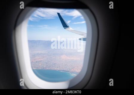 Vue sur l'aile de l'avion et les nuages à travers le hublot. Banque D'Images