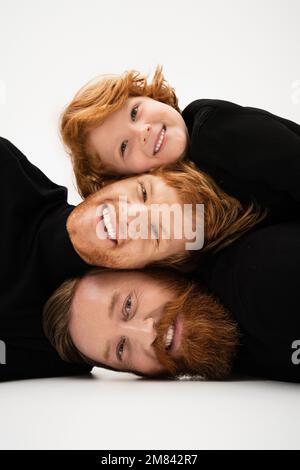 joyeux redhead hommes et garçon dans les chandails noirs ayant le plaisir tout en posant sur fond gris clair, image de stock Banque D'Images