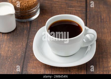 Café instantané ou granulé dans une tasse blanche sur une table en bois Banque D'Images