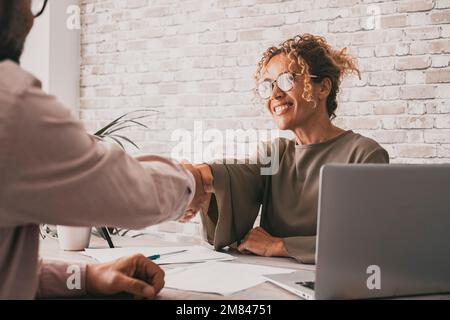 Une femme et un homme heureux signant un accord tenant les mains. Femme d'affaires et client à la réception de conclure le contrat avec un sourire. Confiance et conce d'affaires Banque D'Images