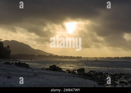 Le soleil couchant traverse les nuages et illumine l'océan sur l'île de Rarotonga, îles Cook Banque D'Images