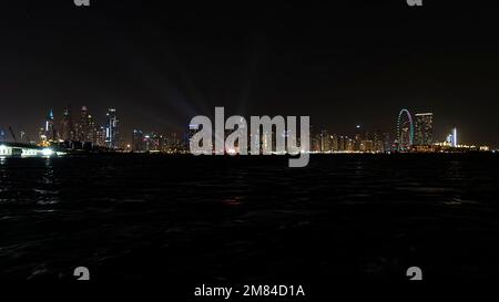 L'horizon de la marina de Dubaï après le coucher du soleil avec une mer en premier plan. Magnifique vue nocturne sur les gratte-ciels de Dubaï depuis la mer. Banque D'Images