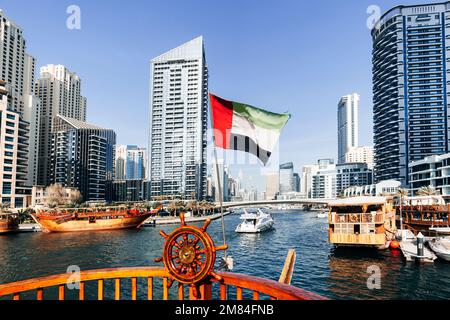 Vue depuis un bateau en mer jusqu'au drapeau des Émirats arabes Unis et au paysage urbain avec la tour. excursion en bateau sur un yacht. Banque D'Images