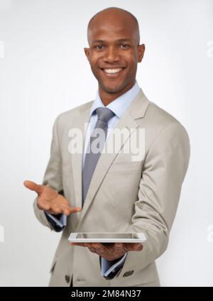 Souhaitez-vous voir cette nouvelle technologie ? Jeune homme attrayant présentant une tablette et souriant. Banque D'Images