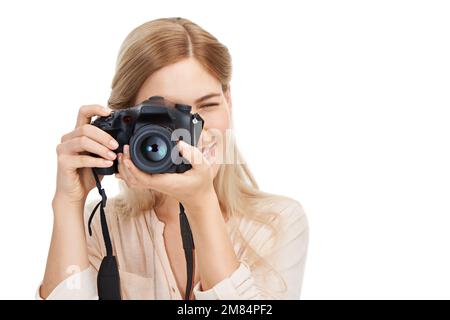 Souriez. Photo en studio d'une jeune photographe féminine qui prend des photos isolées sur blanc. Banque D'Images