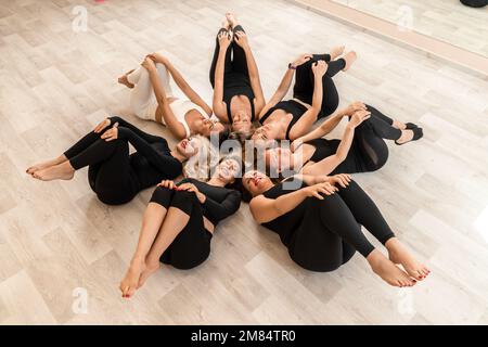 Sept femmes heureuses se trouvent sur le dos, sur le sol, la tête étant pressée. Banque D'Images