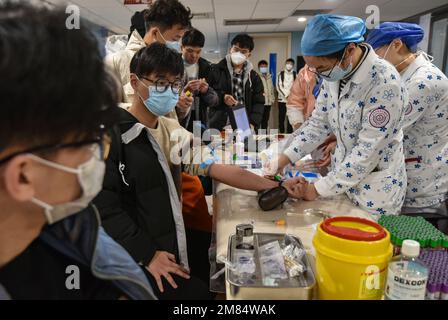 Fuyang, Chine. 12th janvier 2023. Une infirmière prélève du sang d'un jeune homme pour faire des bilans de santé avant d'être admise dans l'armée. Ces jeunes veulent devenir soldats, mais ils doivent subir des contrôles physiques stricts et d'autres contrôles avant de pouvoir devenir soldats. Crédit : SOPA Images Limited/Alamy Live News Banque D'Images