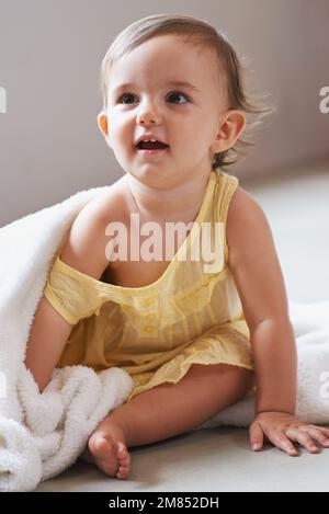 Elle ne marche jamais n'importe où sans sa couverture. une petite fille mignonne assise sur le sol jouant avec sa couverture. Banque D'Images