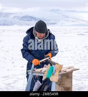 Les habitants pêchent pour « le pot », bien que des trous dans la glace de mer à Uummannaq dans l'ouest du Groenland. Banque D'Images