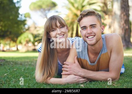 Détente dans le parc. Portrait d'un jeune couple heureux couché dans le parc. Banque D'Images