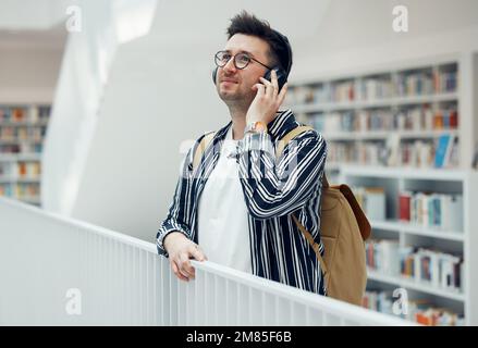 Écouteurs, étudiant et bibliothèque universitaire ou recherche pour l'apprentissage. Bâtiment de campus d'école, musique et diffusion de chansons en direct d'un Banque D'Images