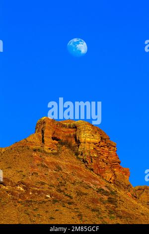 Une vue magnifique sur la lune au-dessus des falaises jaunes dans un ciel bleu clair Banque D'Images