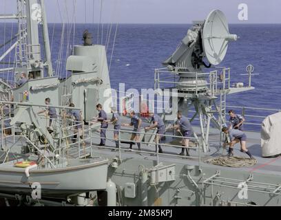 Les membres de l'équipage transportent sur une ligne à bord de la frégate de missiles guidés australiens HMAS SYDNEY (FFG-03) au cours d'un exercice de reconstitution en cours avec le porte-avions à propulsion nucléaire USS CARL VINSON (CVN-70). Derrière lui se trouve le Mark 16 Phalanx dans le système d'armes. Pays : Océan Pacifique (POC) Banque D'Images