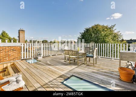 une terrasse en bois avec chaises et une piscine extérieure dans la partie centrale de la terrasse, entourée de piquets blancs Banque D'Images