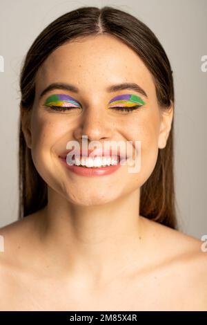 Portrait d'un jeune modèle à l'état de taches de rousseur avec un sourire de visage et des yeux fermés isolés sur le gris Banque D'Images