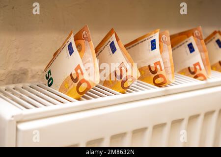 Gros plan du radiateur blanc et des billets de 50 euros. Concept de chauffage et d'électricité coûteux. Banque D'Images