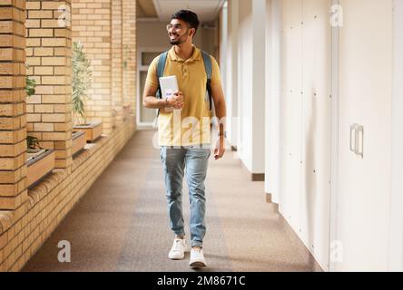 Étudiant à l'université, étudiant et indien marchant avec un sourire et un sac à dos dans le couloir du campus. Gen z homme heureux au sujet de l'éducation, l'apprentissage et Banque D'Images