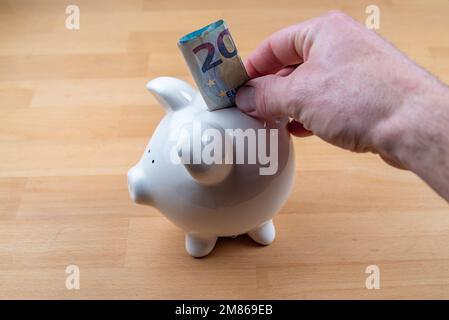 La main met 20 euros de facture dans la banque de piggy Banque D'Images