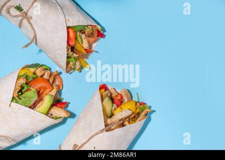 Classique rue nourriture shawarma ou burrito, sandwich sain enveloppé dans la tortilla pain plat avec viande de poulet frite, légumes frais, sauce, sur b vif Banque D'Images