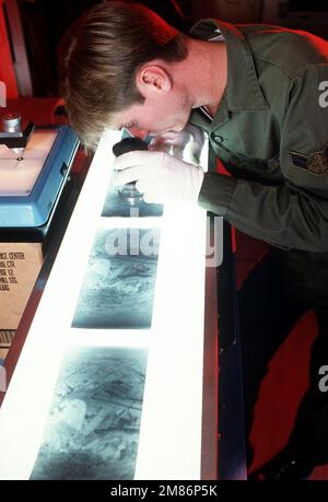 A ÉTATS-UNIS La photo-interprète de la Force aérienne examine un ensemble de négatifs de reconnaissance sur une table lumineuse pendant la rencontre aérienne de reconnaissance 86. Des pilotes de reconnaissance, des interprètes photo et des équipes de maintenance des États-Unis La Force aérienne, la Garde nationale aérienne, la Marine et les Marines, la Royal Australian Air Force et le Royaume-Uni participent à l'événement parrainé par le Commandement aérien tactique. Objet opération/série: RECONNAISSANCE AIR MEET '86 base: Base aérienne de Bergstrom État: Texas (TX) pays: États-Unis d'Amérique (USA) Banque D'Images